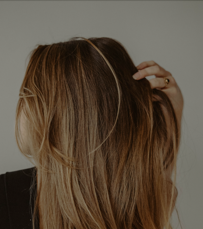 woman running fingers through brown hair after using hair loss products