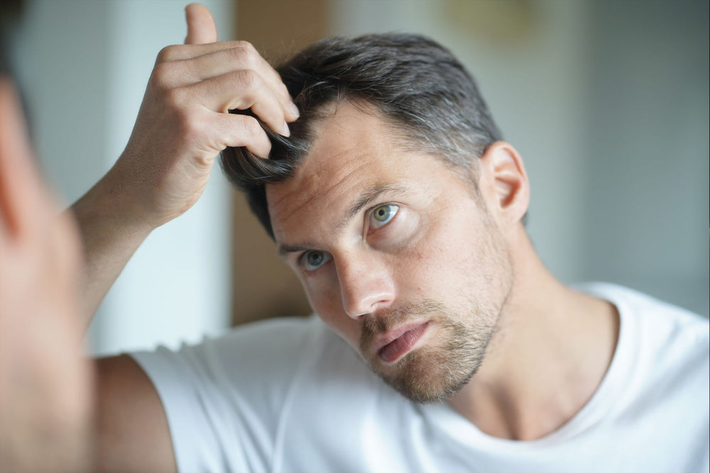 man looking at hair line in mirror, hair loss in men