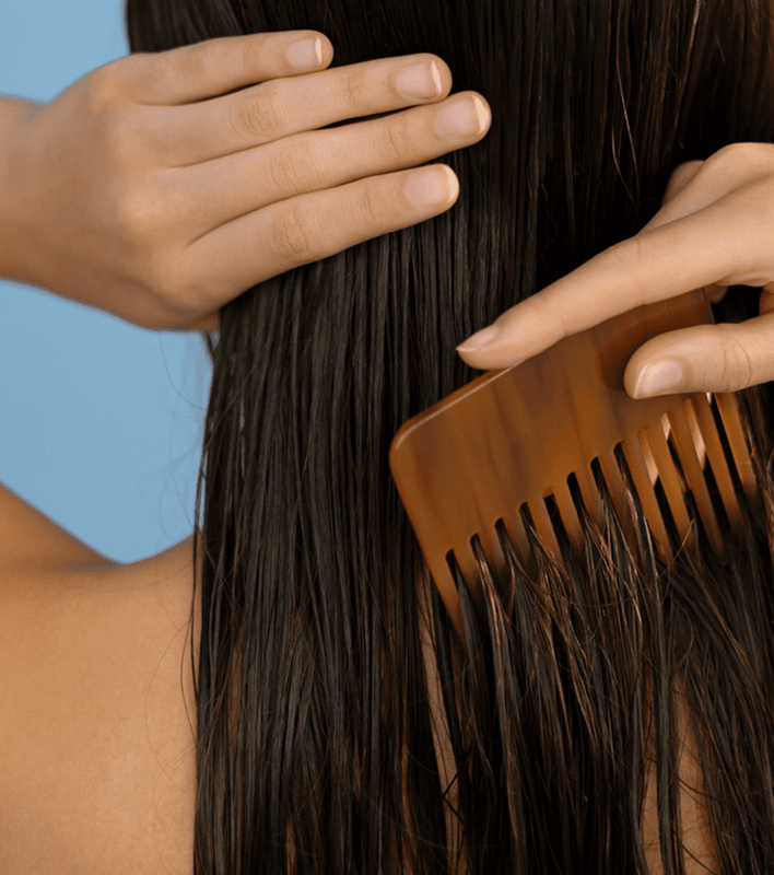 woman using large comb in hair to stop hair from shedding