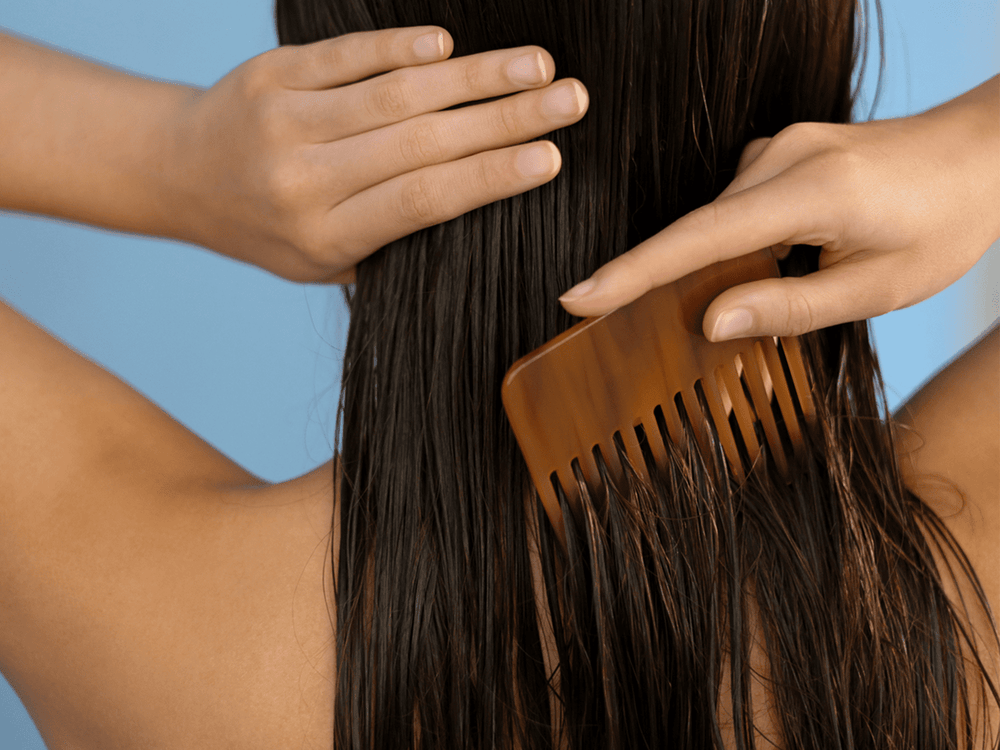 woman using large comb in hair to stop hair from shedding
