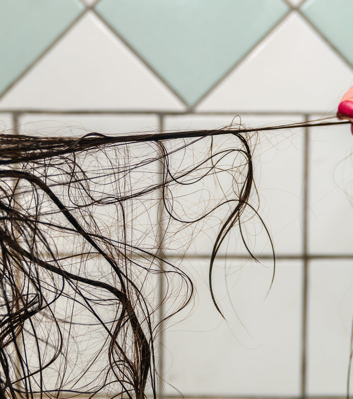 Woman pulling hair out to show effects of shower water and hair loss