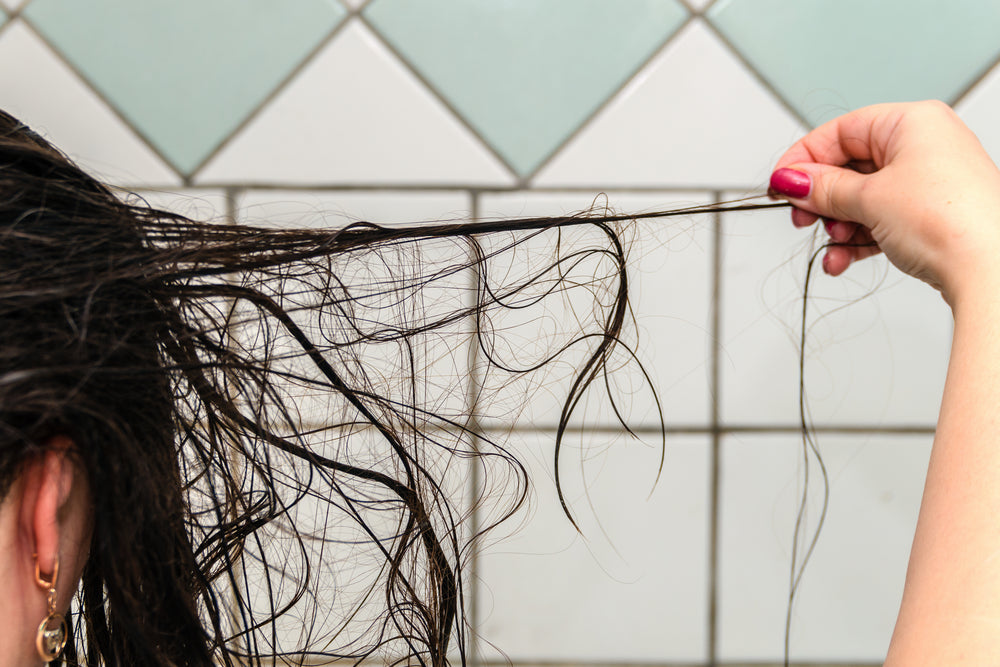 Woman pulling hair out to show effects of shower water and hair loss