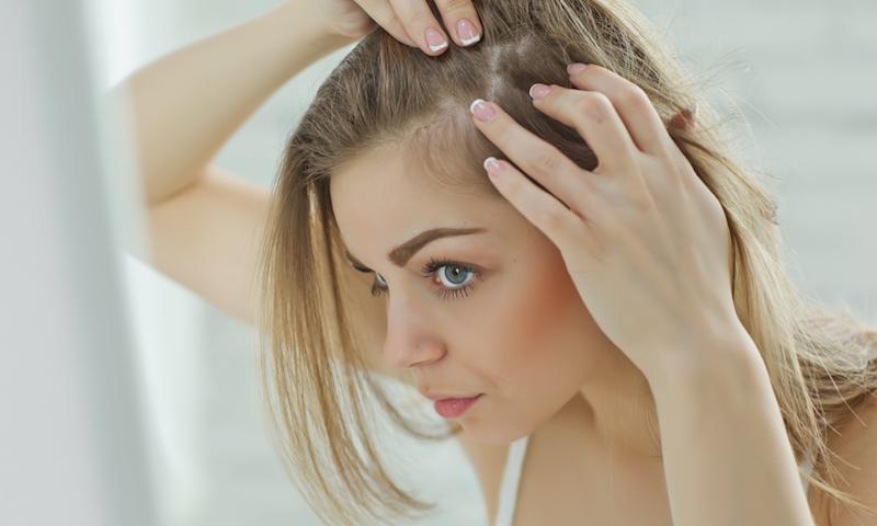Blonde woman examining hair line for womens hair loss